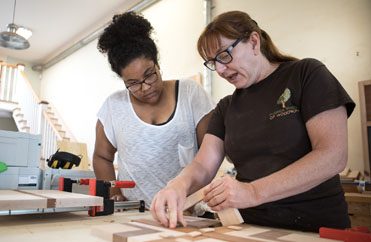 Women learning Woodwork Female woodworking instructor teaches student during class