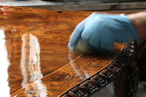 finishing wood Instructor wearing gloves French polishing a wooden table